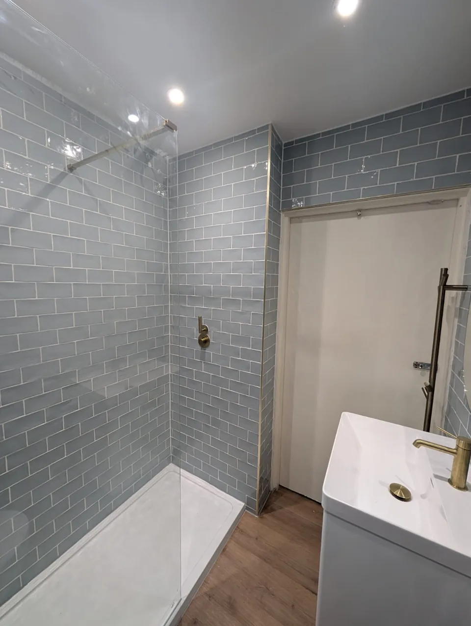 Walk-in shower with blue wall tiles and white tray