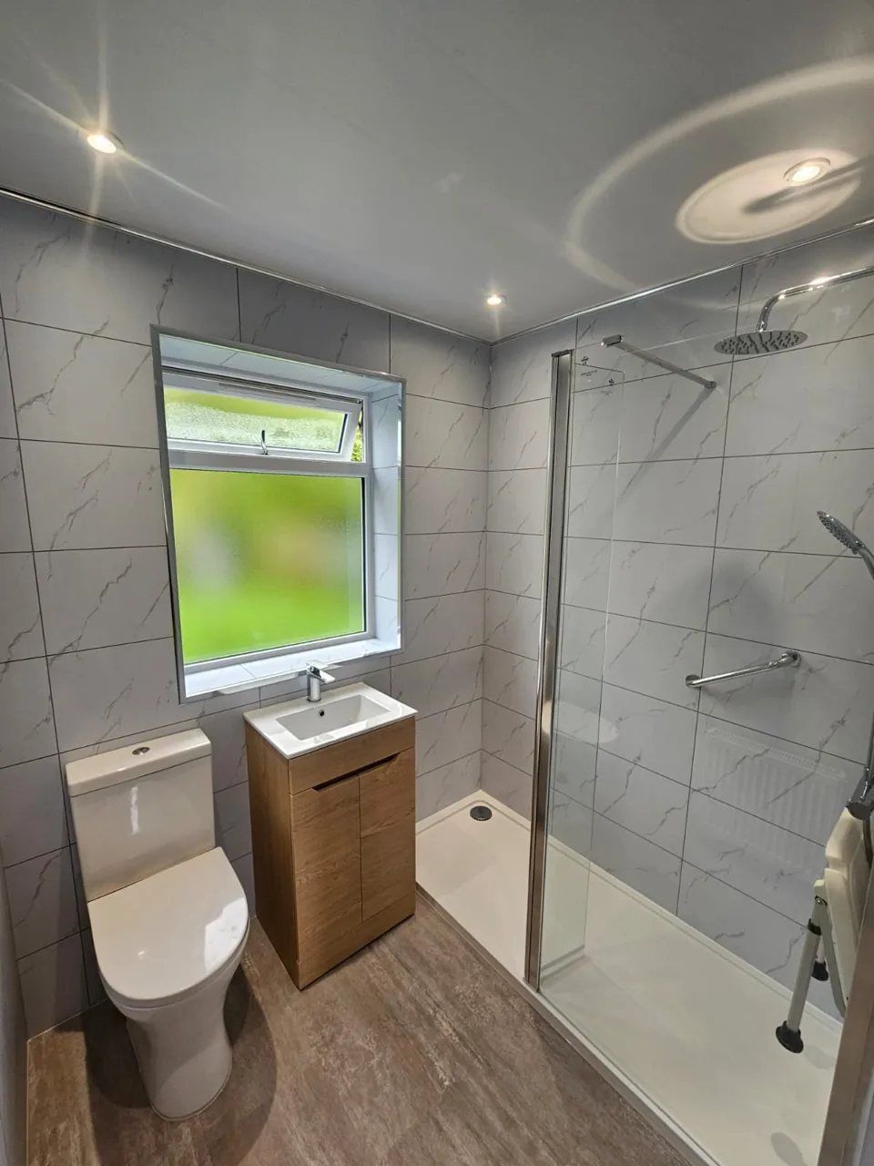 Compact shower room with oak vanity and marble-effect walls